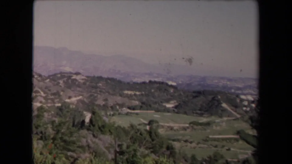 A 1967 home-movie frame looks across Los Angeles-area fields and hills toward hazy mountains and distant development.