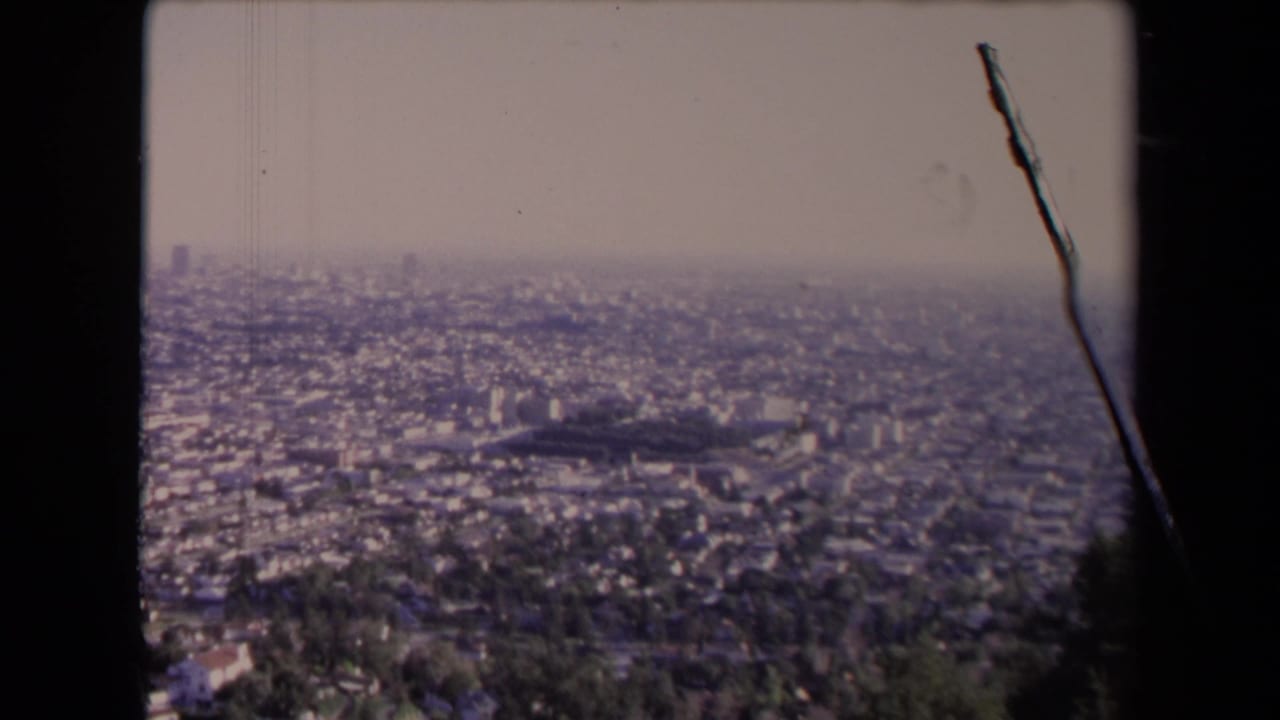 Elevated view over a hazy Los Angeles cityscape with dense neighborhoods and distant buildings.