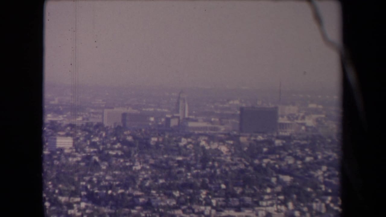 Hazy aerial view of Los Angeles with dense neighborhoods and distant high-rises.