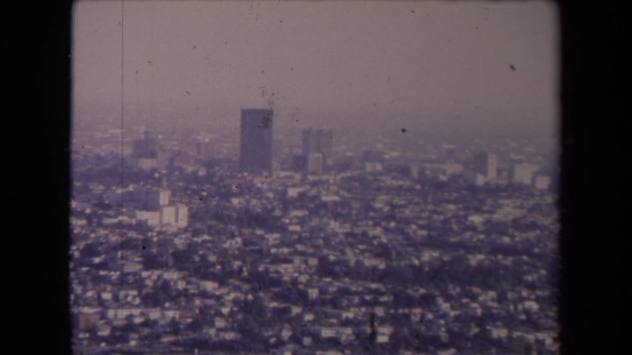 Hazy aerial view over dense city buildings with distant high-rises.