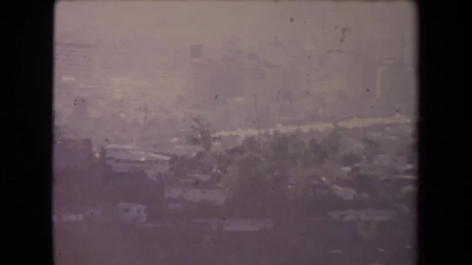 Faded 8mm aerial view over Los Angeles with visible roads, trees, buildings, and purple-tinted film wear.