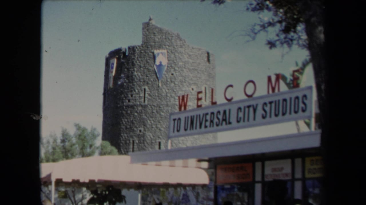 Universal City Studios welcome sign in front of a castle-like stone tower.