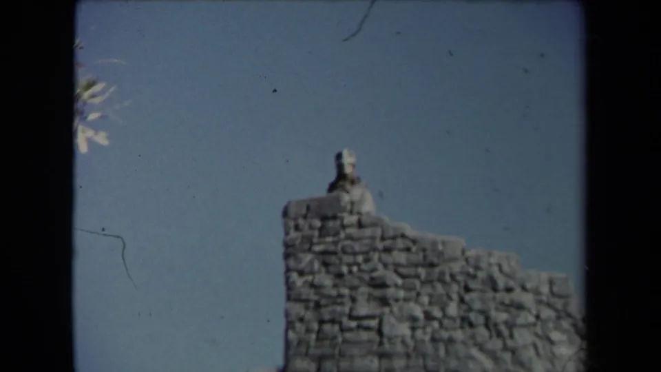 1967 Los Angeles 8mm frame isolating the small knight figure atop the Universal City Studios castle-like tower.