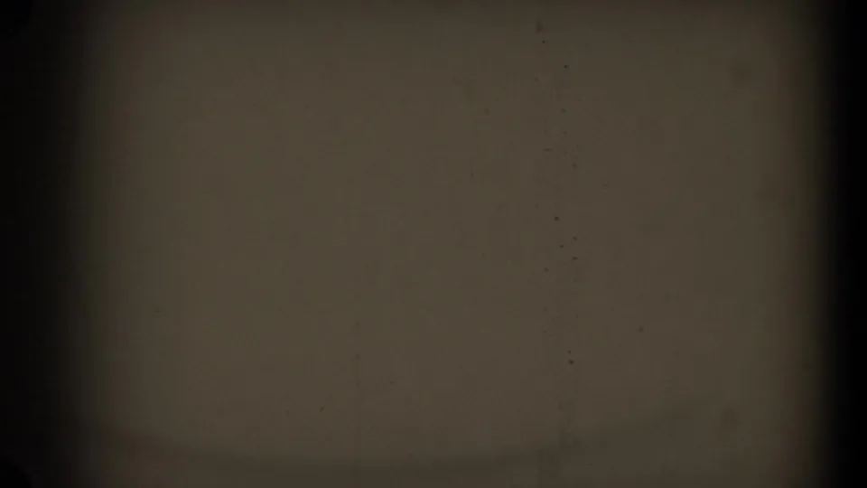 A mostly obscured 8mm frame with dark borders, central vertical banding, and faint film texture before the sidewalk scene appears.