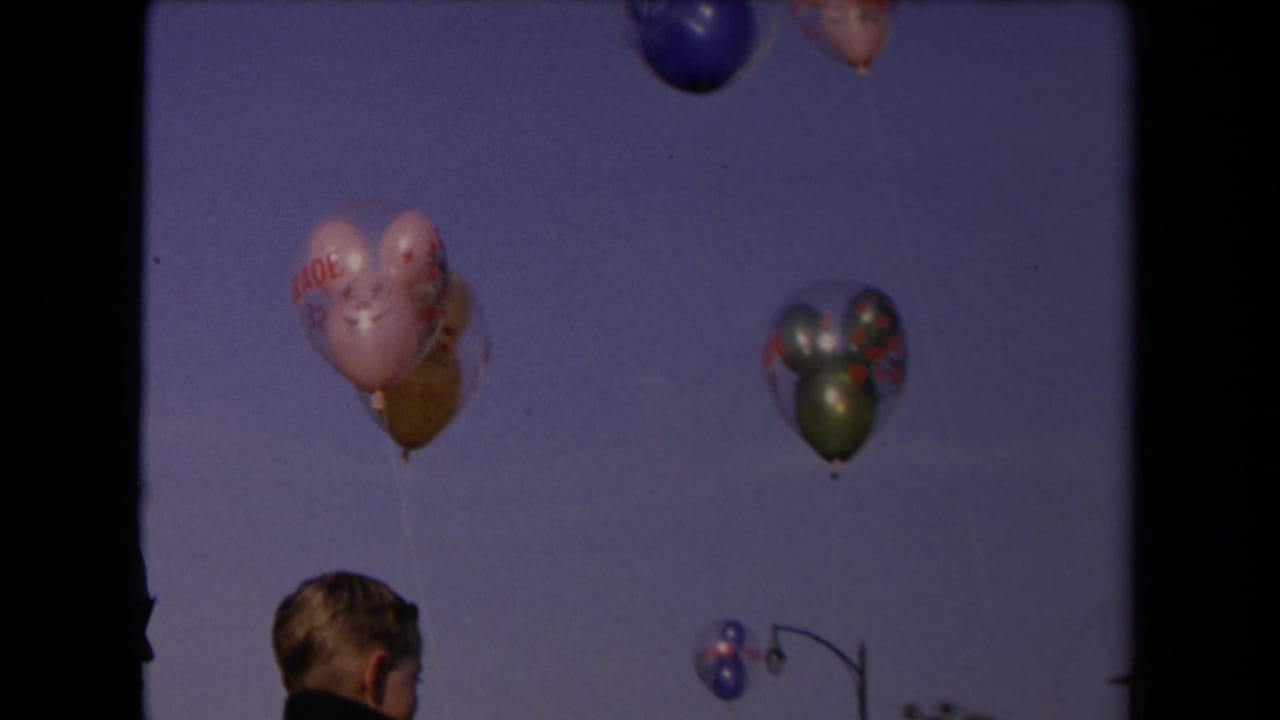 In 1967 Los Angeles home-movie footage, a young boy is partly visible beneath several balloons drifting upward.