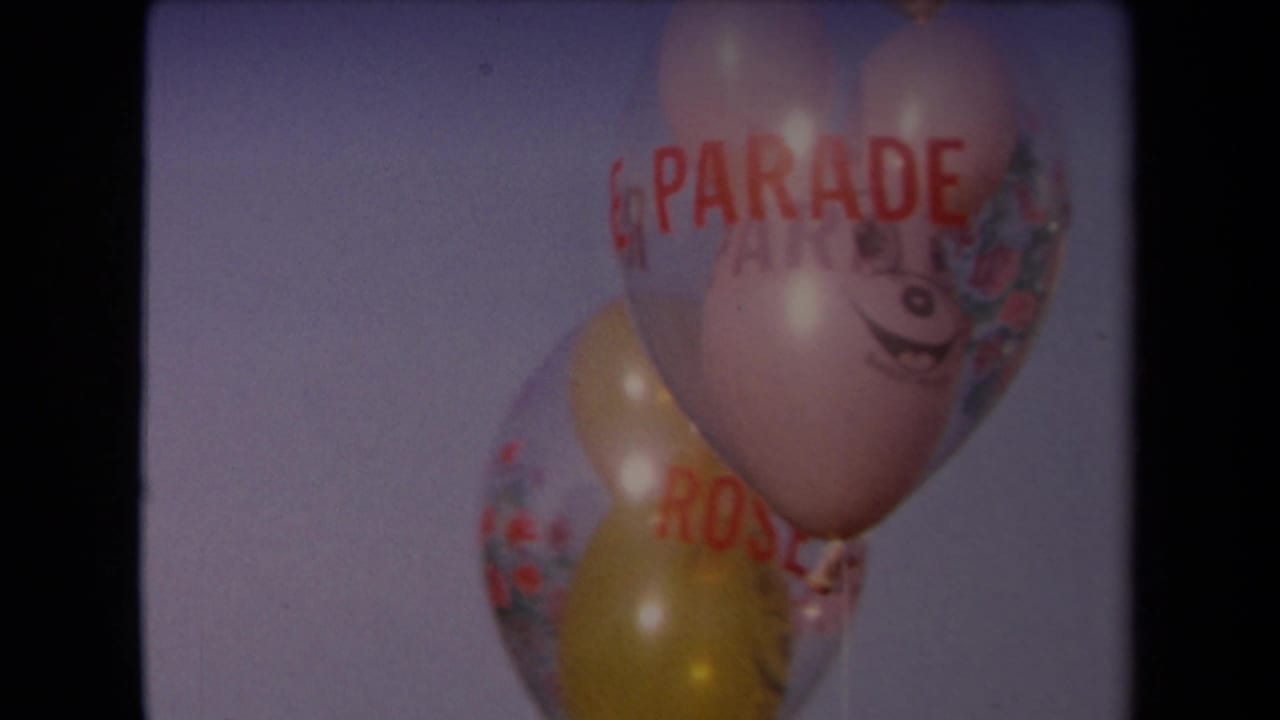 Clustered balloons with red parade lettering fill the frame against the sky in this 1967 Los Angeles 8mm shot.