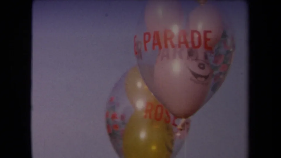 Clustered balloons with red parade lettering fill the frame against the sky in this 1967 Los Angeles 8mm shot.