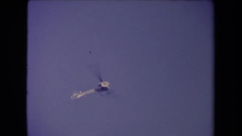 A lone helicopter appears in soft focus against blue sky in 1967 Los Angeles home-movie footage.