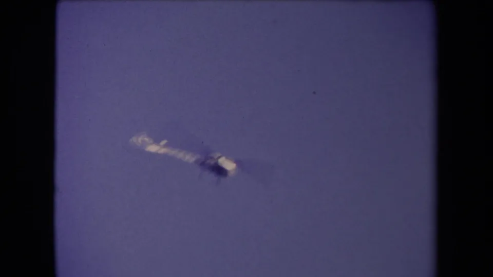A small aircraft or helicopter appears against the sky in 1967 Los Angeles home-movie footage.