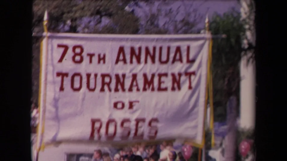 Tournament of Roses banner fills the frame in 1967 Los Angeles home-movie footage, with partial crowd details below.