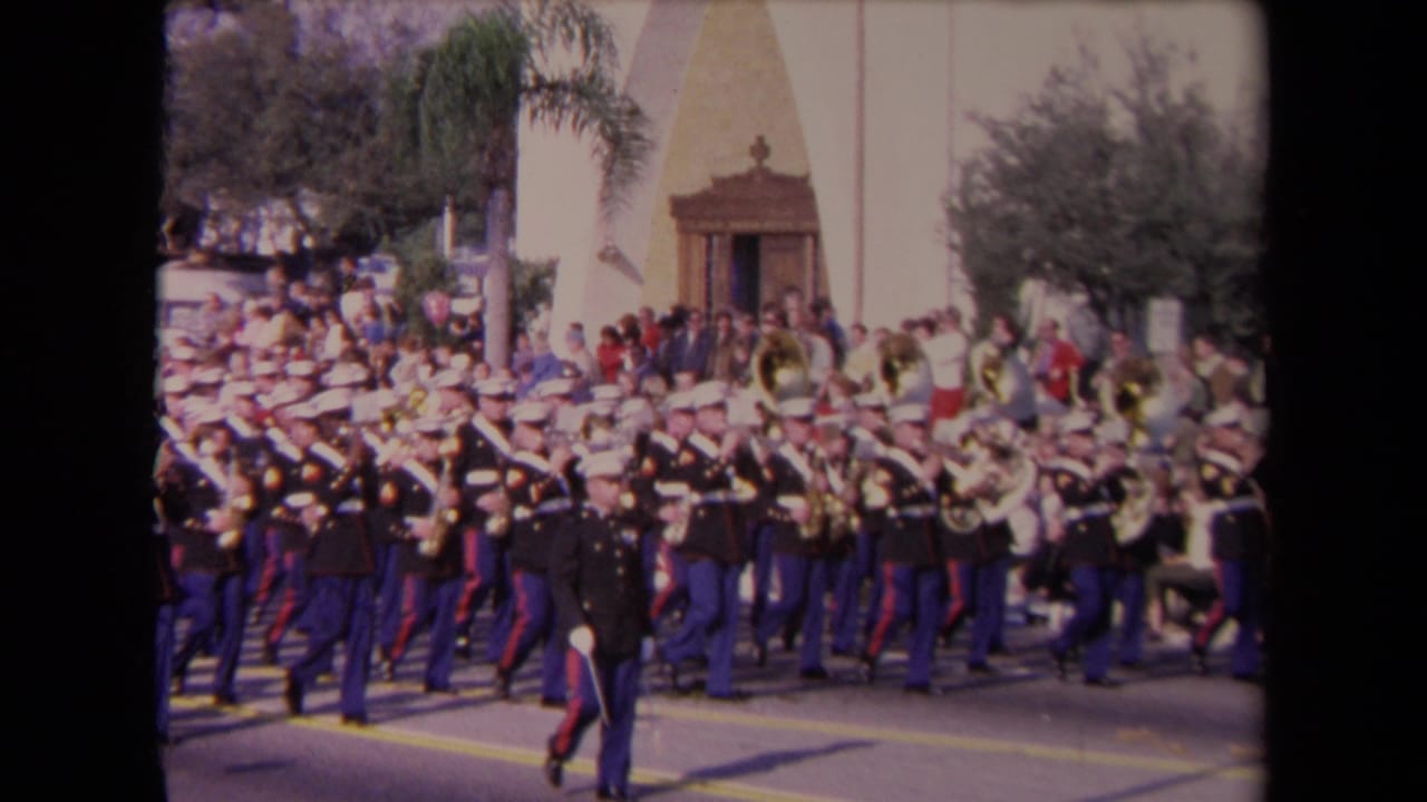 1967 Los Angeles parade footage shows a United States Marine Corps band marching past spectators near a building entrance and palm trees.