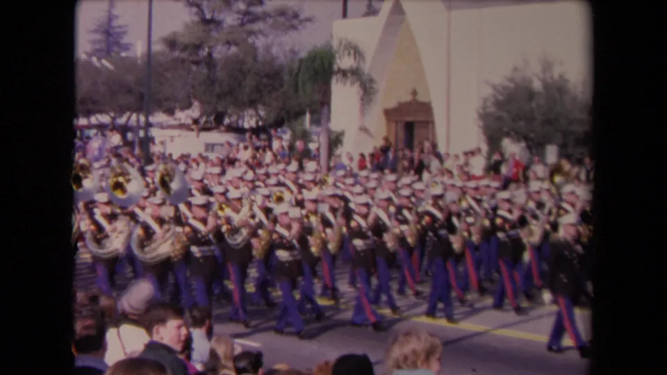 The closing frame shows the Marine band continuing down the Los Angeles street as nearby spectators appear at the bottom of the home-movie frame.
