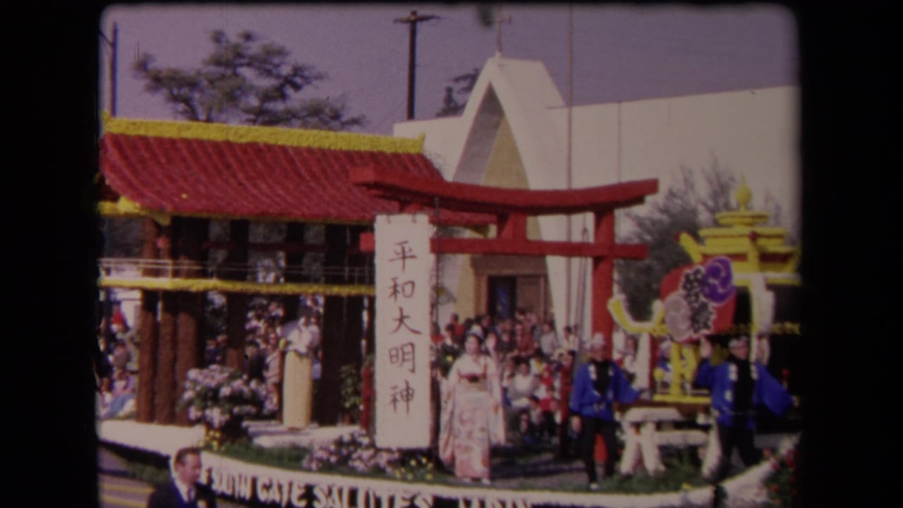 1967 Los Angeles parade float with a red pavilion roof, torii gate, Japanese-character sign, floral trim, and participants posed for spectators.