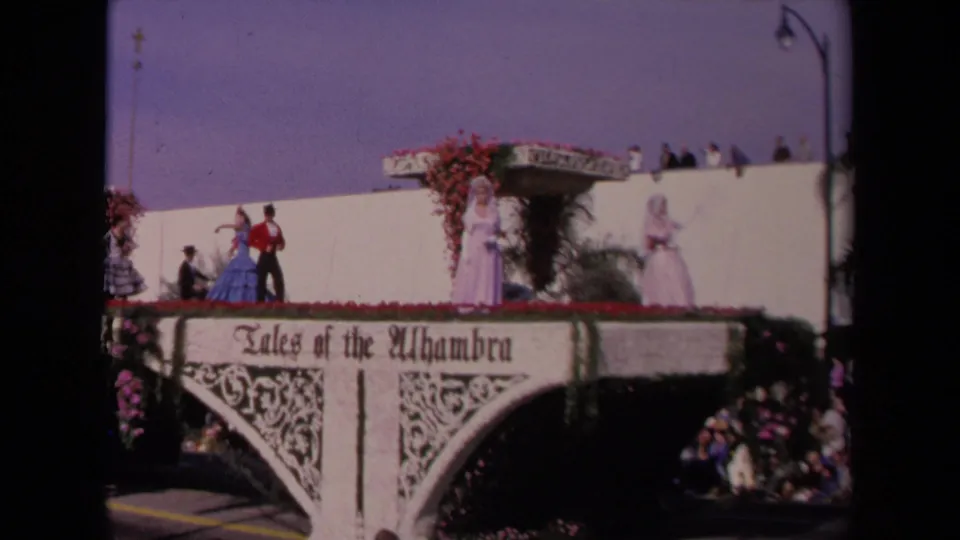 1967 Los Angeles parade float marked Tales of the Alhambra, with performers in formal and period-style costumes above spectators.