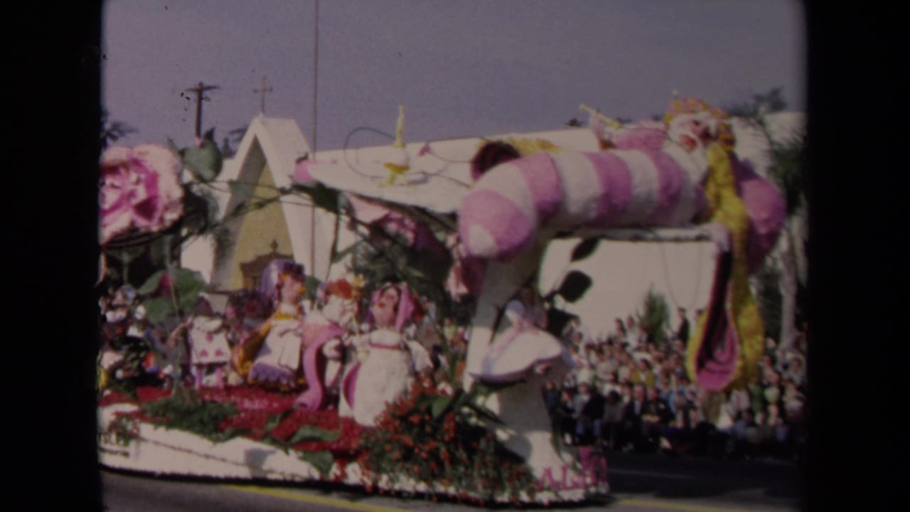 1967 Los Angeles 8mm frame showing a fantasy-themed parade float with pink floral decorations and a crowd watching from the curb.