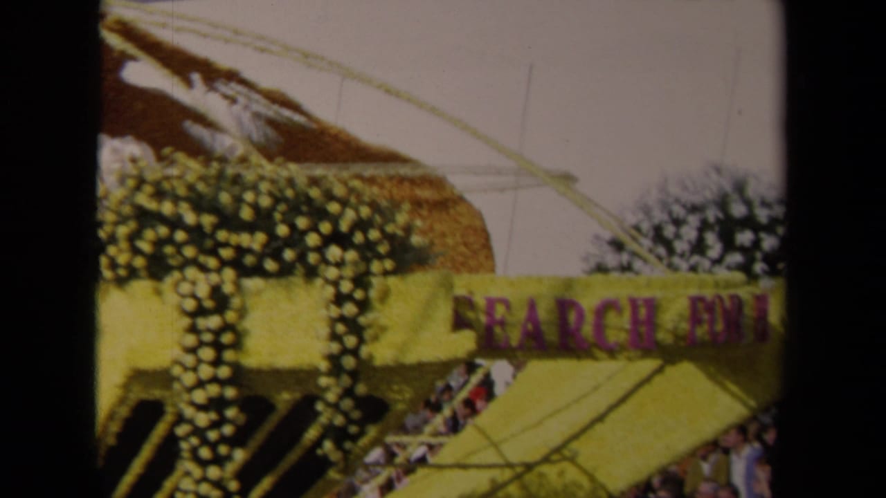 A yellow and purple Lions International float passes in 1967 Los Angeles, with floral decoration and part of a globe-shaped structure visible.