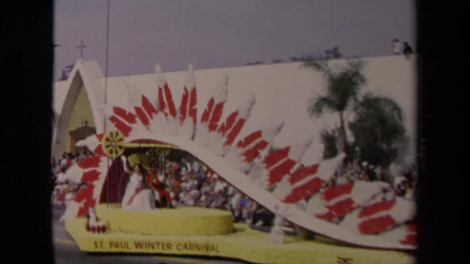 Wide 1967 Los Angeles street view of a St. Paul Winter Carnival float with riders beneath a red-and-white arch and spectators lining the route.