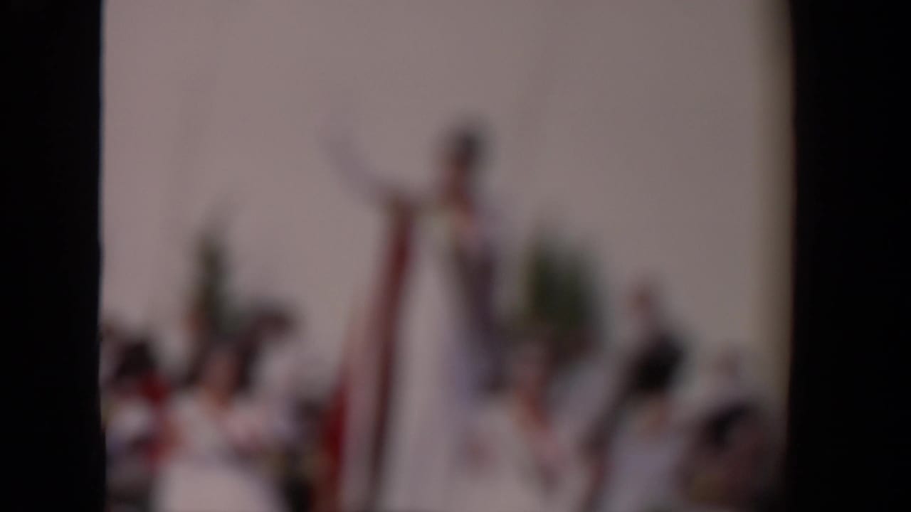 Out-of-focus 8mm frame from a 1967 Los Angeles parade, with blurred figures and dark contact-sheet borders.
