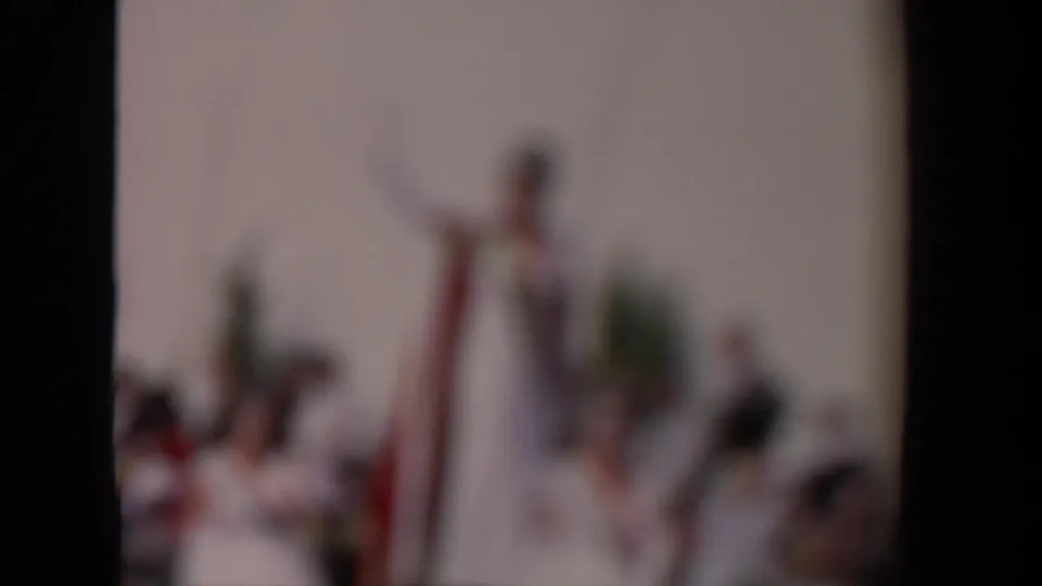 Out-of-focus 8mm frame from a 1967 Los Angeles parade, with blurred figures and dark contact-sheet borders.