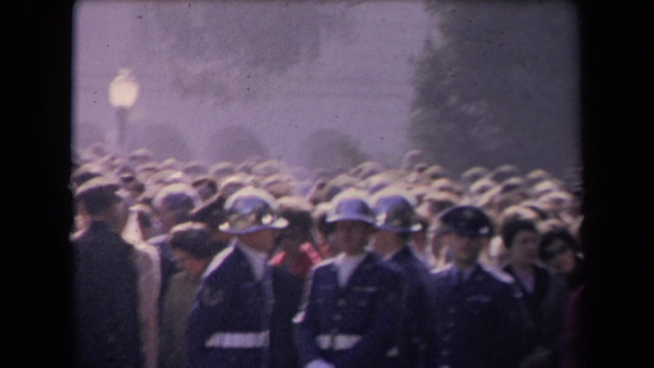 Soft 8mm frame of a dense outdoor crowd with uniformed guards visible in front, associated by metadata with the 1967 Reagan inauguration in Sacramento.