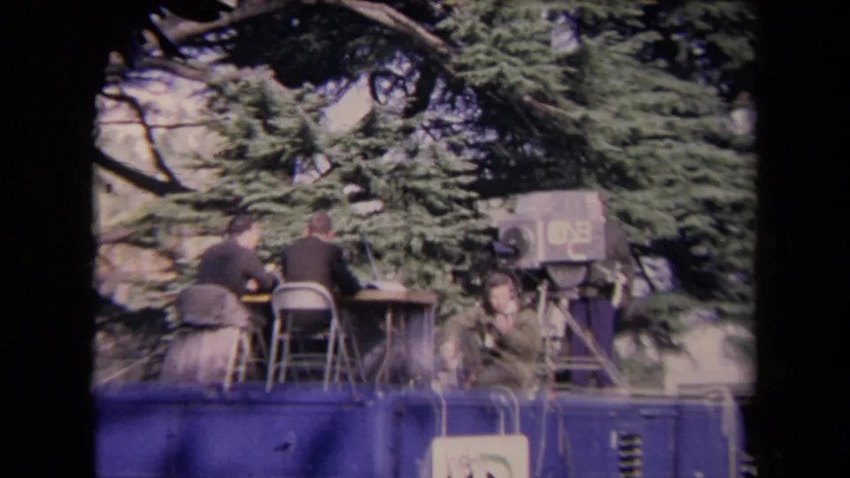 1967 Sacramento inauguration footage showing a raised mobile news platform with seated crew and a large broadcast camera under trees.