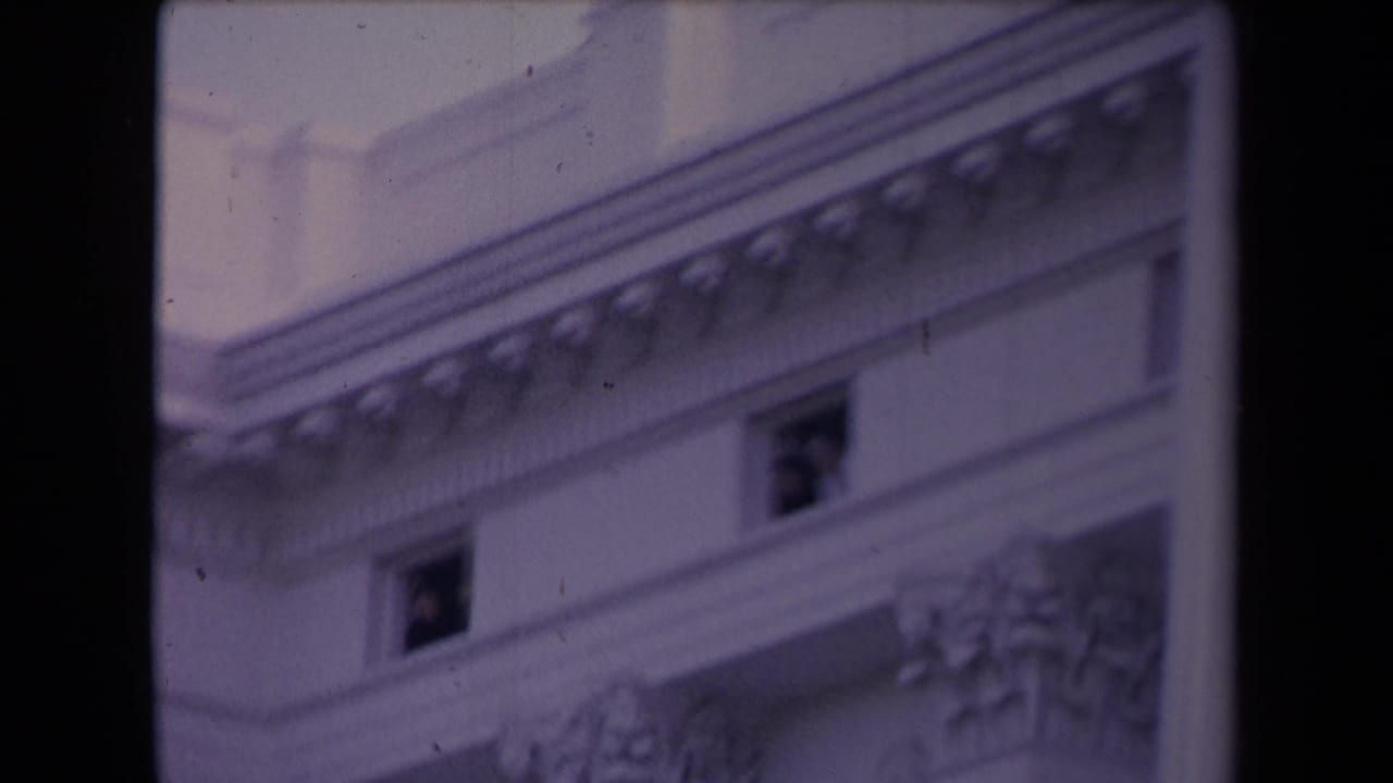 Purple-shifted 8mm frame showing a classical civic-looking facade with decorative cornice detail and small dark windows.