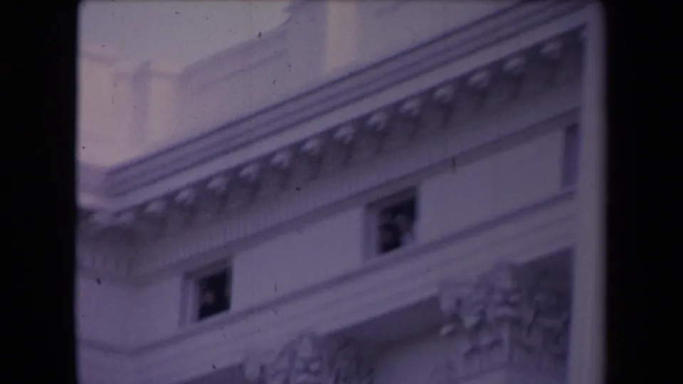 Purple-shifted 8mm frame showing a classical civic-looking facade with decorative cornice detail and small dark windows.