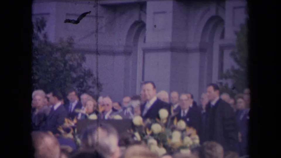 1967 Sacramento inauguration footage showing suited men, floral arrangements, and a crowd before an arched public building.