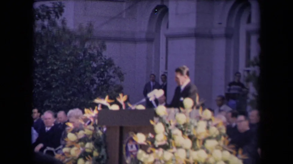 Ronald Reagan appears at a podium with microphones, flowers and seated attendees during a reported 1967 inauguration event.