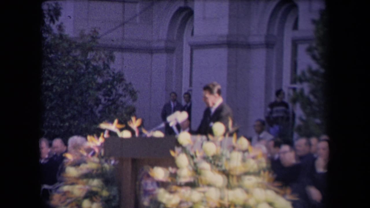 The speaker, identified by metadata as Ronald Reagan, stands at a decorated podium in front of a formal outdoor audience.