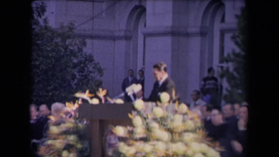 The speaker, identified by metadata as Ronald Reagan, stands at a decorated podium in front of a formal outdoor audience.
