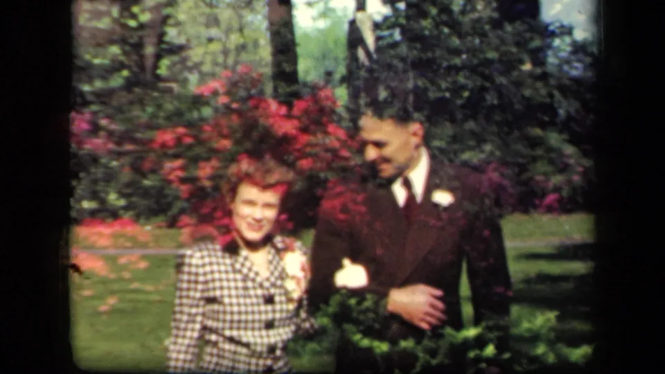 In supplied 1941 New York home-movie footage, a young woman in a checkered jacket walks beside a suited man with a boutonniere.