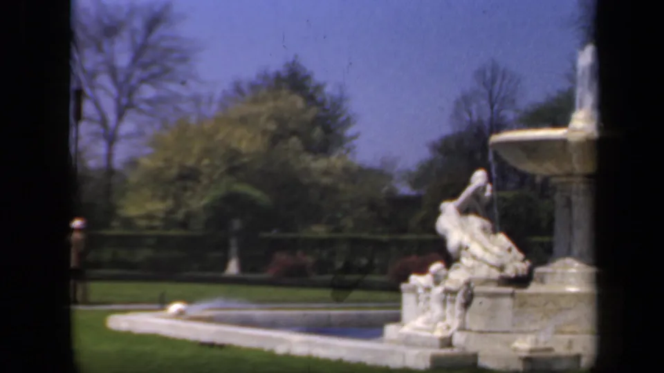 The final frame shows part of the New York garden fountain, a reclining statue, clipped lawn, trees, and the edge of the 8mm frame.