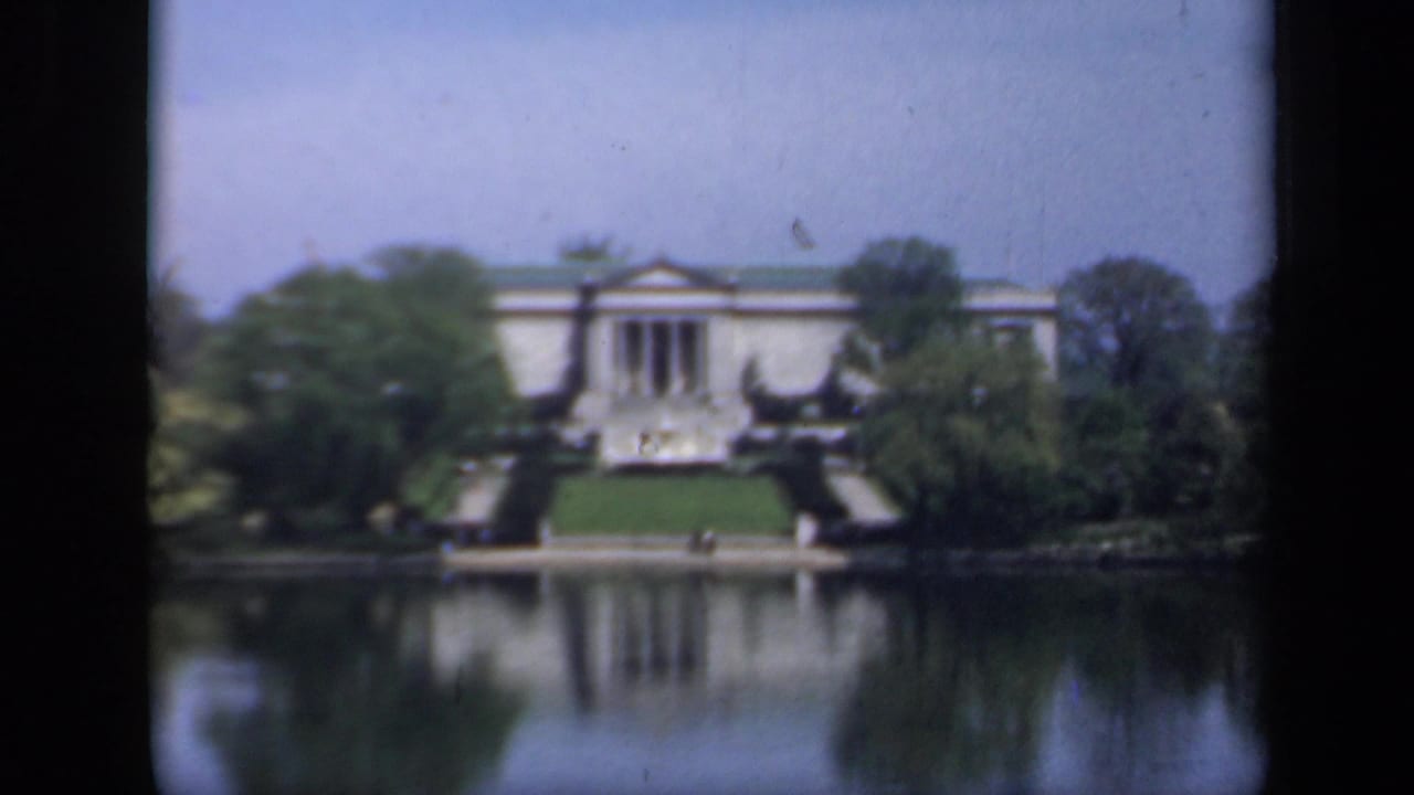A distant New York architectural exterior from 1941 shows columns, steps, trees, and a lake reflection in soft 8mm color.