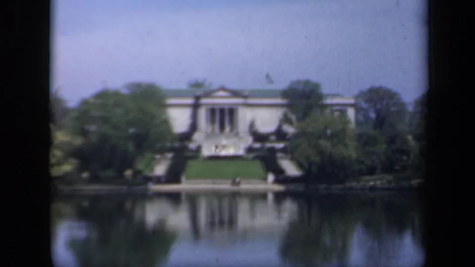 A distant New York architectural exterior from 1941 shows columns, steps, trees, and a lake reflection in soft 8mm color.