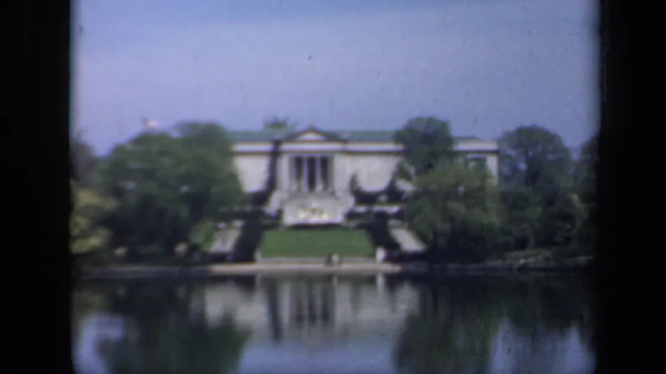 Final frame holds on the same 1941 New York lakeside architectural view, with columns, trees, lawn, and visible 8mm film texture.