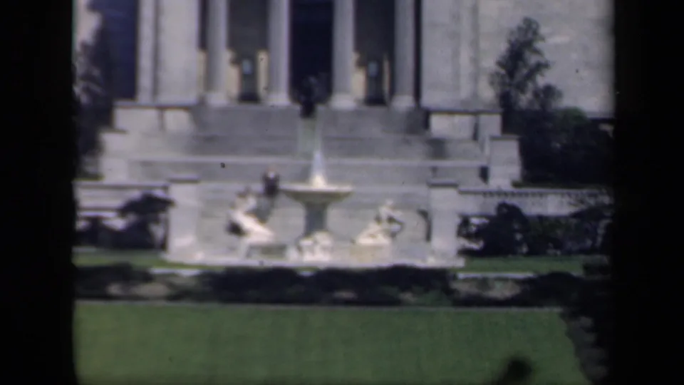 Soft 1941 New York 8mm frame showing the fountain, lawn, staircase, and columned facade from a visitor viewpoint.