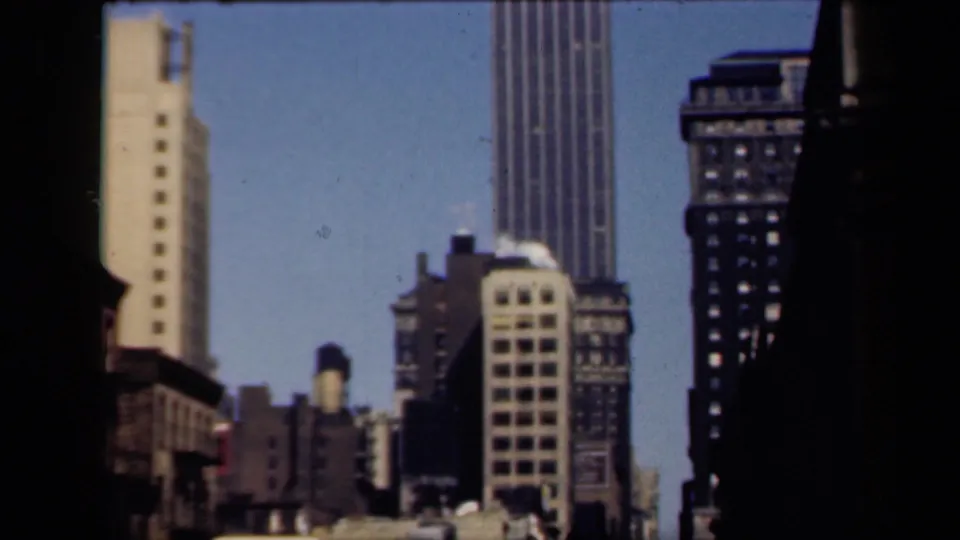 1941 New York 8mm frame showing a dense cluster of buildings, rooftop water tanks, and street signals from an elevated viewpoint.