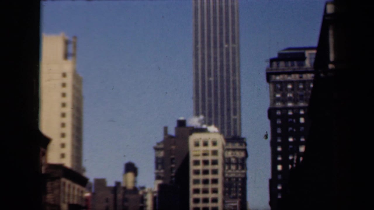 Urban skyline with a tall skyscraper partly framed by dark vertical shapes.