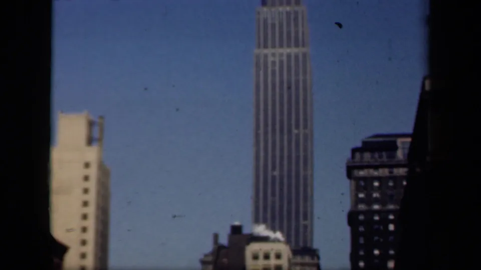 Final 1941 New York frame with a tall ribbed skyscraper, neighboring high-rises, and dark foreground edges enclosing the view.