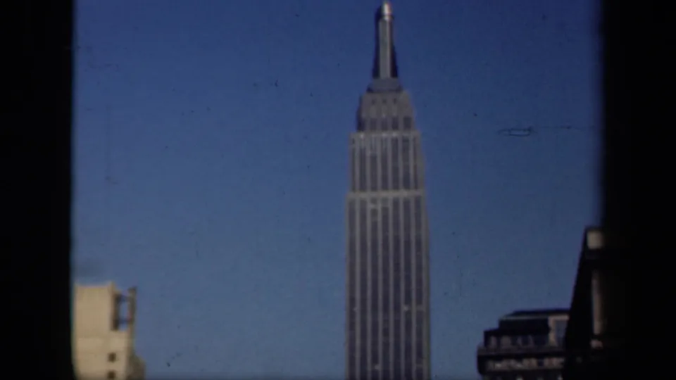 1941 New York 8mm still showing the Empire State Building from a lower window-framed angle with surrounding skyline fragments.