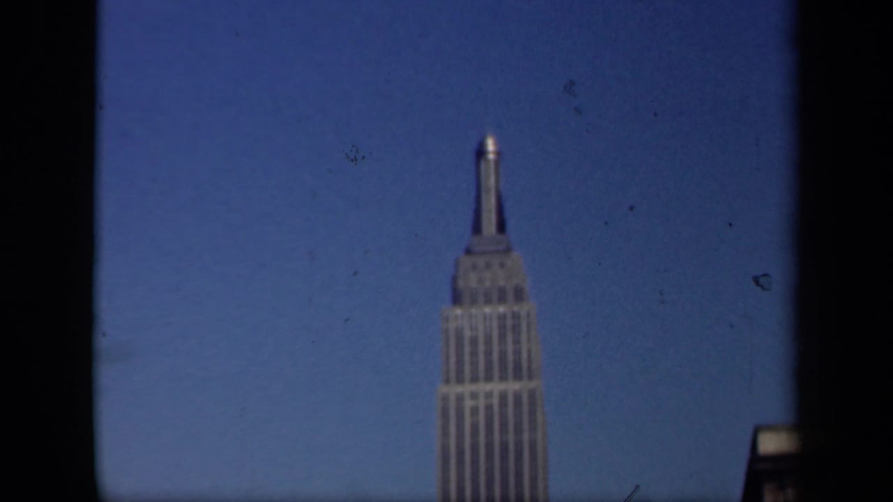 1941 New York frame with the Empire State Building visible beyond a dark window division and open blue sky.