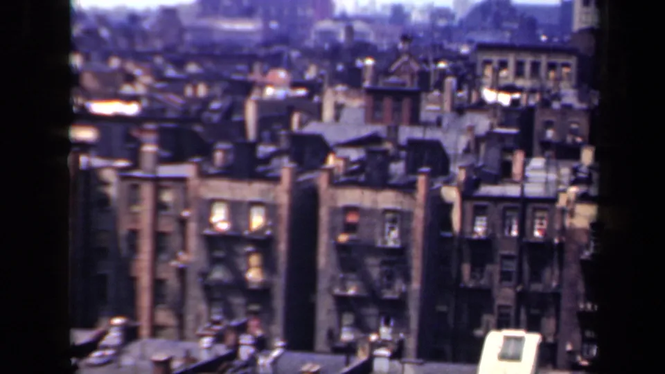 1941 New York city view with closely packed brick buildings, rooftop structures and a dark window mullion in the foreground.