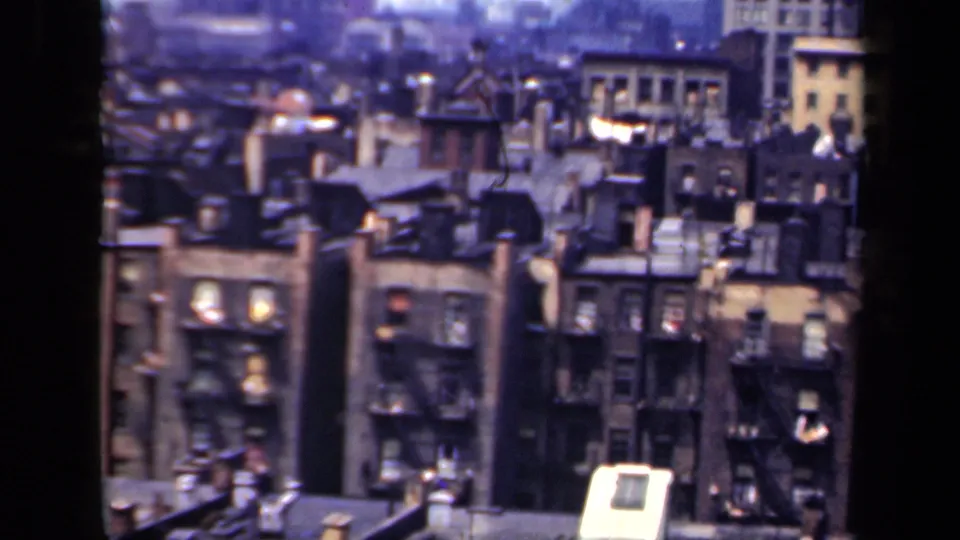 1941 New York 8mm frame with tightly packed apartment buildings, rooftop details and a few illuminated windows at dusk-like light.