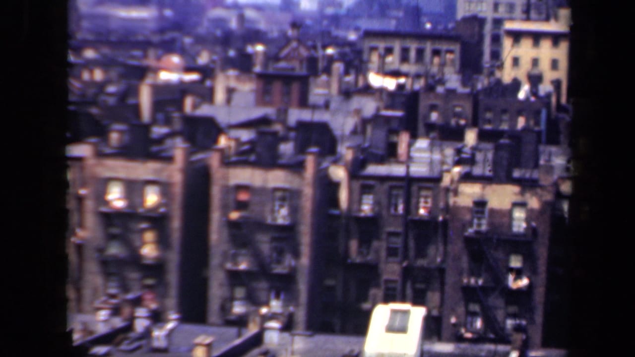 1941 New York high-angle view of masonry apartment buildings, rooftop structures, chimneys, and exterior fire escapes.
