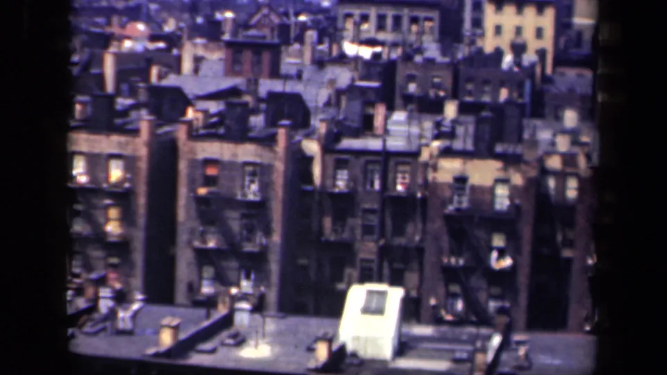 1941 New York elevated view of older masonry apartment buildings, rooftop skylight housing, chimneys, and dark fire escapes.