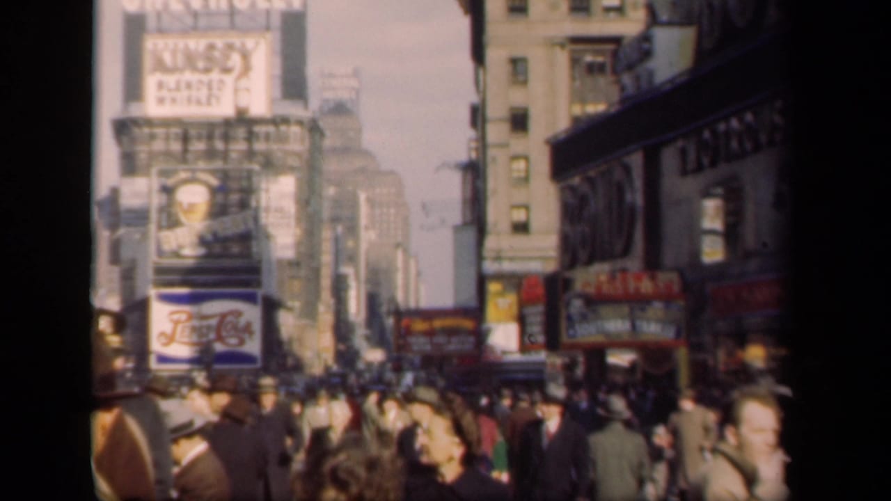1941 Times Square home-movie frame showing a dense crowd below Chevrolet, Kinsey, and Pepsi-Cola advertising signs.