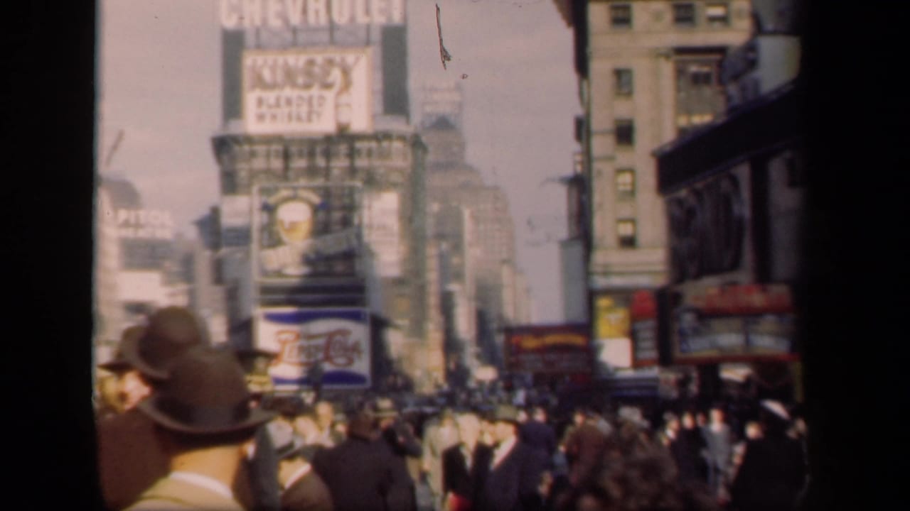 Times Square crowd viewed past men in hats with billboard signs above.