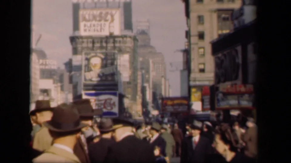 1941 Times Square frame showing suited pedestrians, period hats, and layered commercial signs along a busy city block.