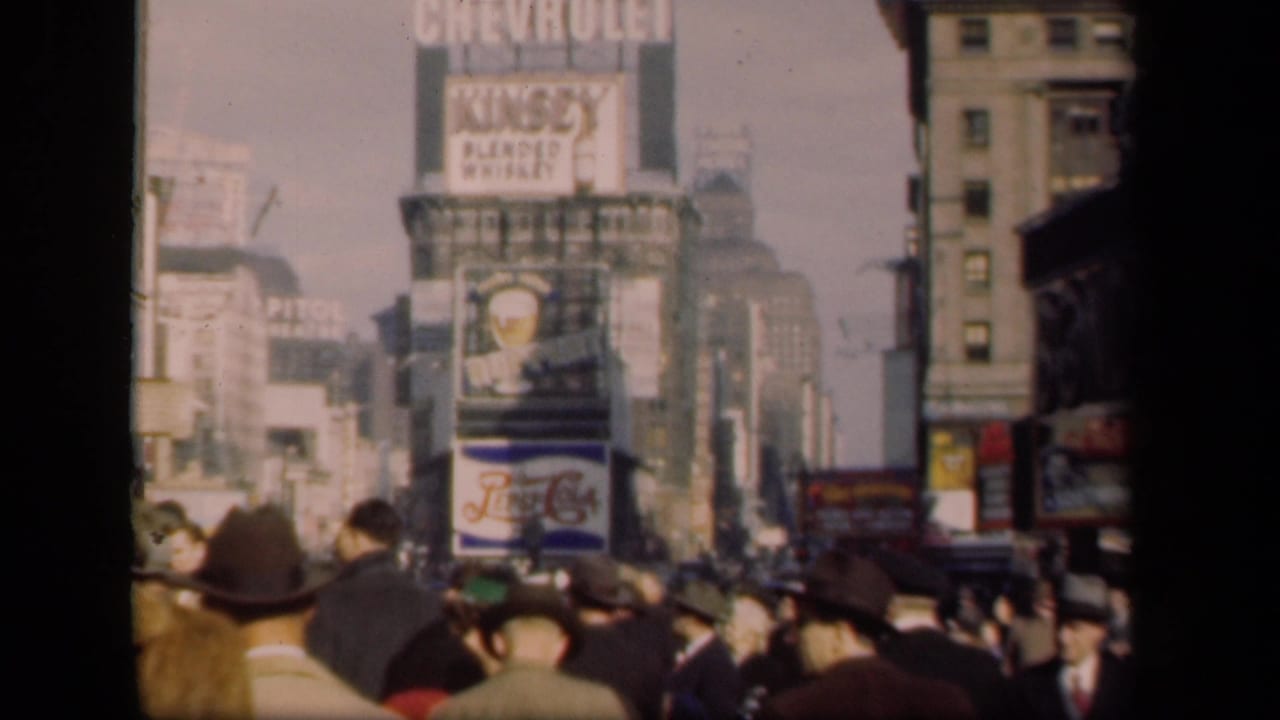 Crowded New York street with pedestrians and large Chevrolet and whiskey billboards.